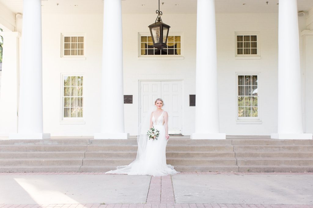 bride poses in front of mansion at Arlington Hall at Lee Park photographed by Courtney Bosworth Photography