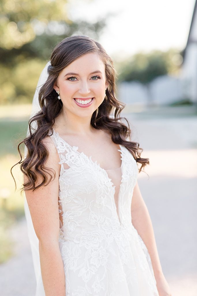 bride with curled hair and veil smiles during bridal portraits