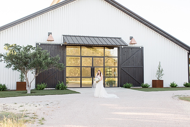 bride poses in front of barn at Mae's Ridge