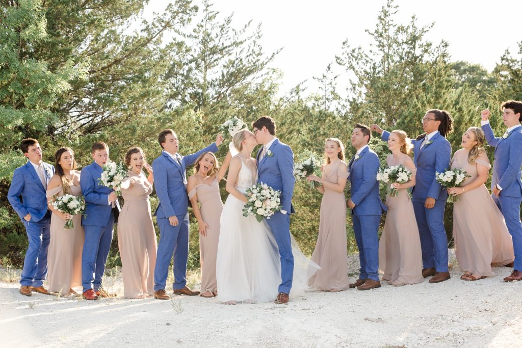 Texas bridal party celebrates while bride and groom kiss