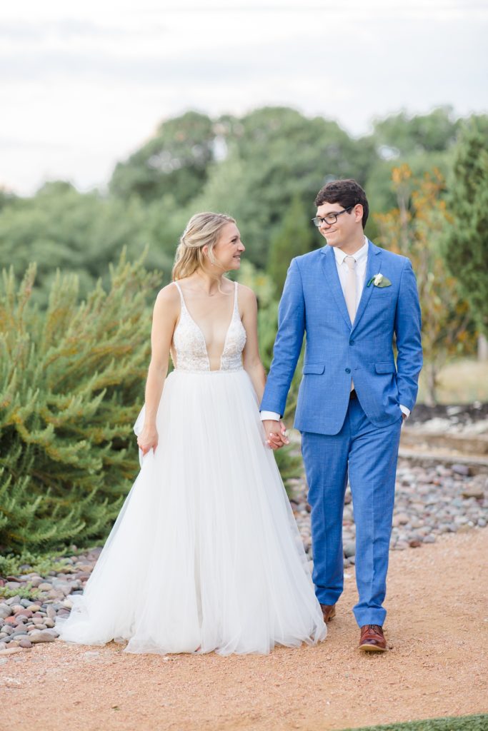 bride and groom hold hands walking towards photographer