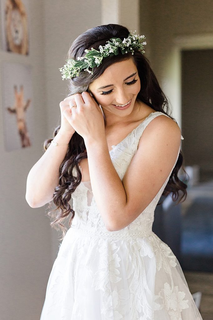 bride in flower crown adjusts earrings before Austin Texas wedding
