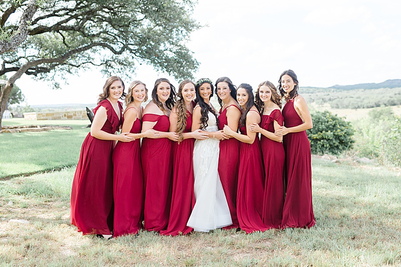 bride poses with 8 bridesmaids in red gowns