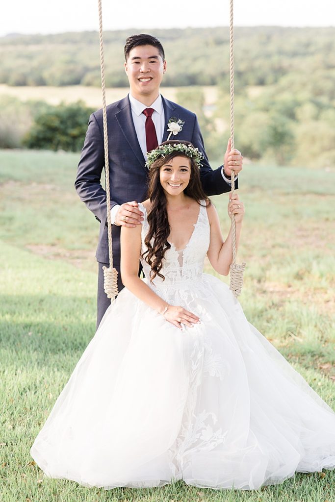 bride and groom sit on wooden swing
