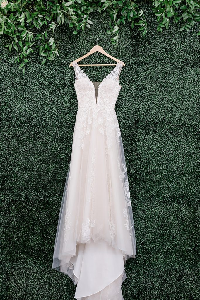 wedding dress hangs on wall with greenery