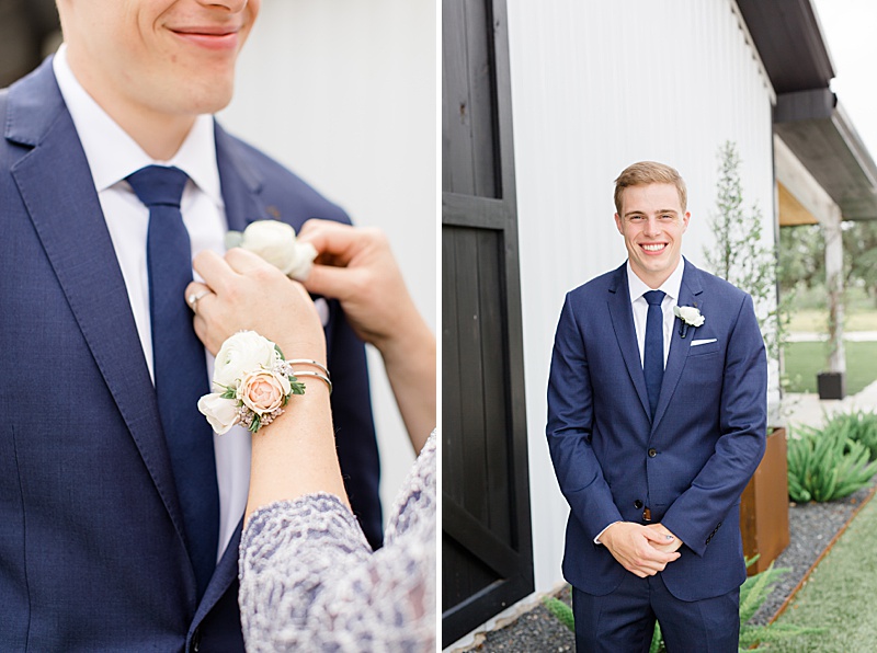 groom's mother puts boutonnière on groom in blue suit