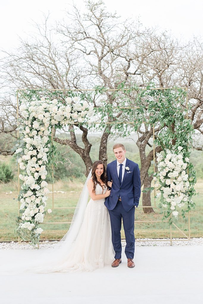 floral arbor with ivory and greenery frames newlyweds in Texas