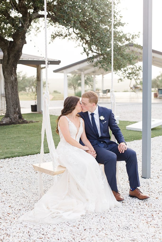 bride and groom sit on wooden swing at Mae's Ridge