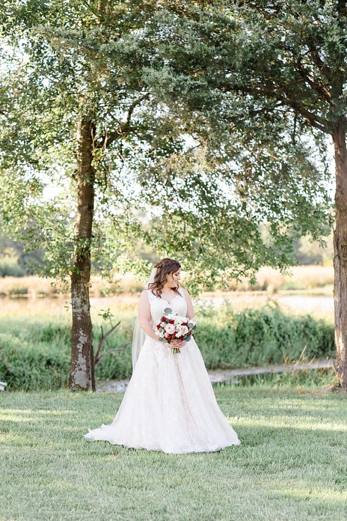 bride holds bouquet and looks over shoulder in field