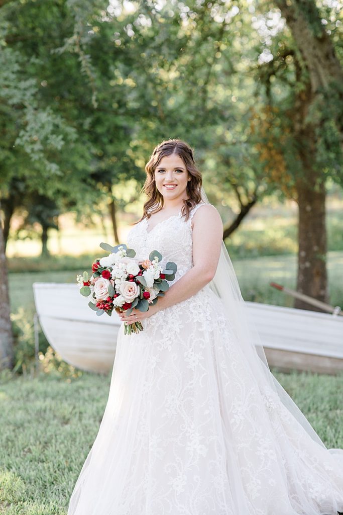 bride poses in front of row boat at The Wildflower