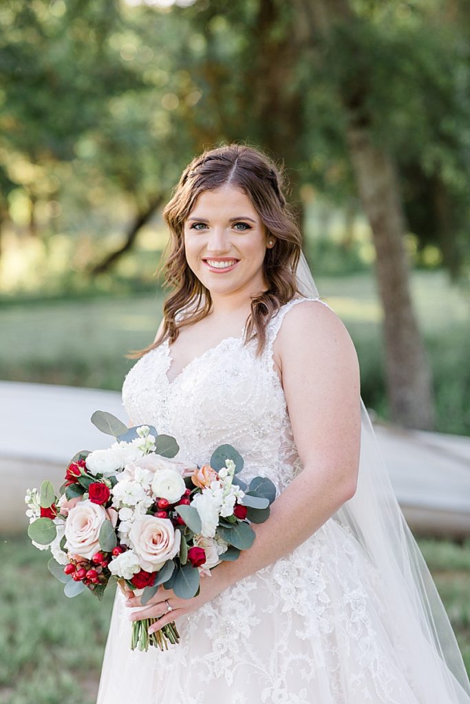 bride holds bouquet with red and pink flowers in Texas