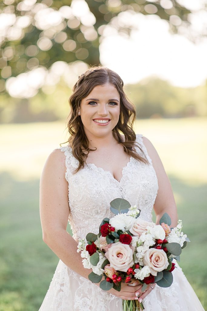 bride holds red and pink bouquet