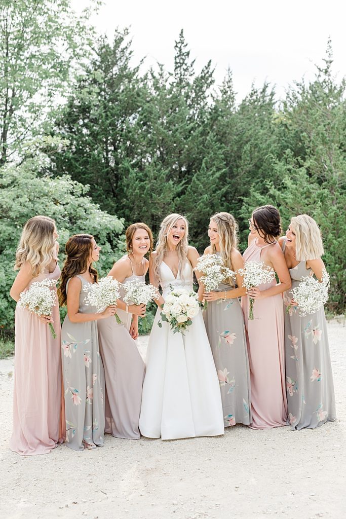 bridesmaids in mismatched pastel gowns laugh with bride