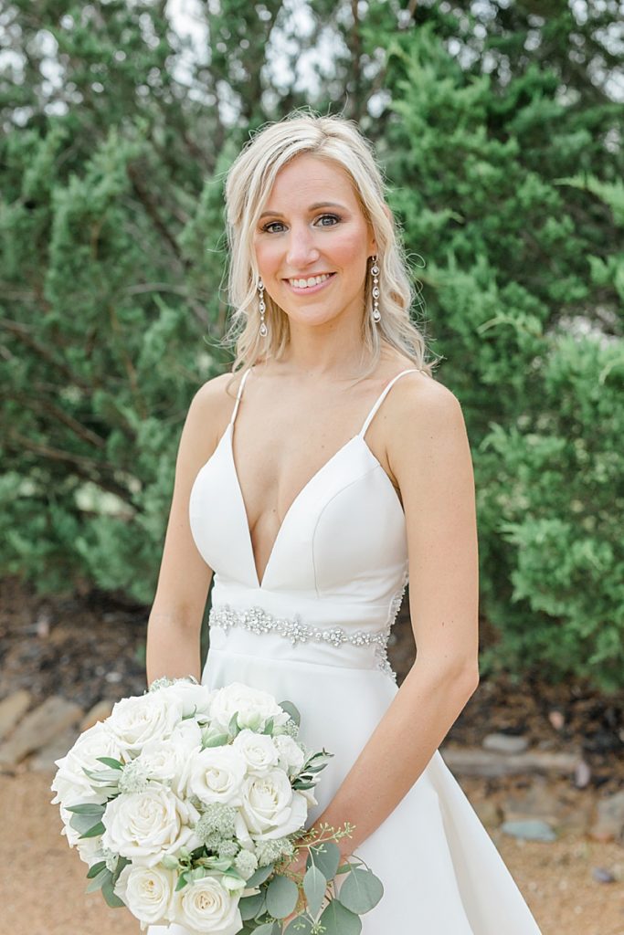 bride holds bouquet of ivory roses