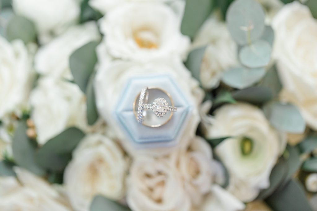 wedding ring rests on pale blue ring box on ivory flowers