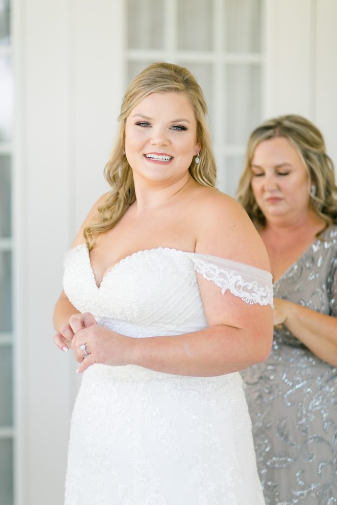 mother of the bride adjusts wedding gown for bride