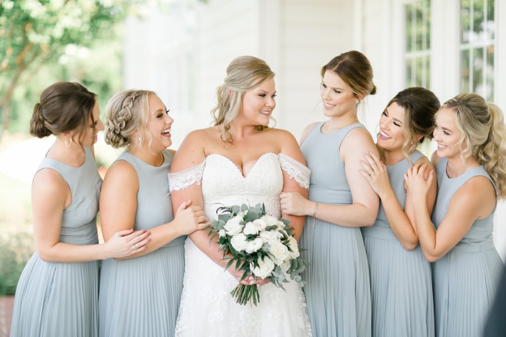 bridesmaids in dusty blue pose with bride