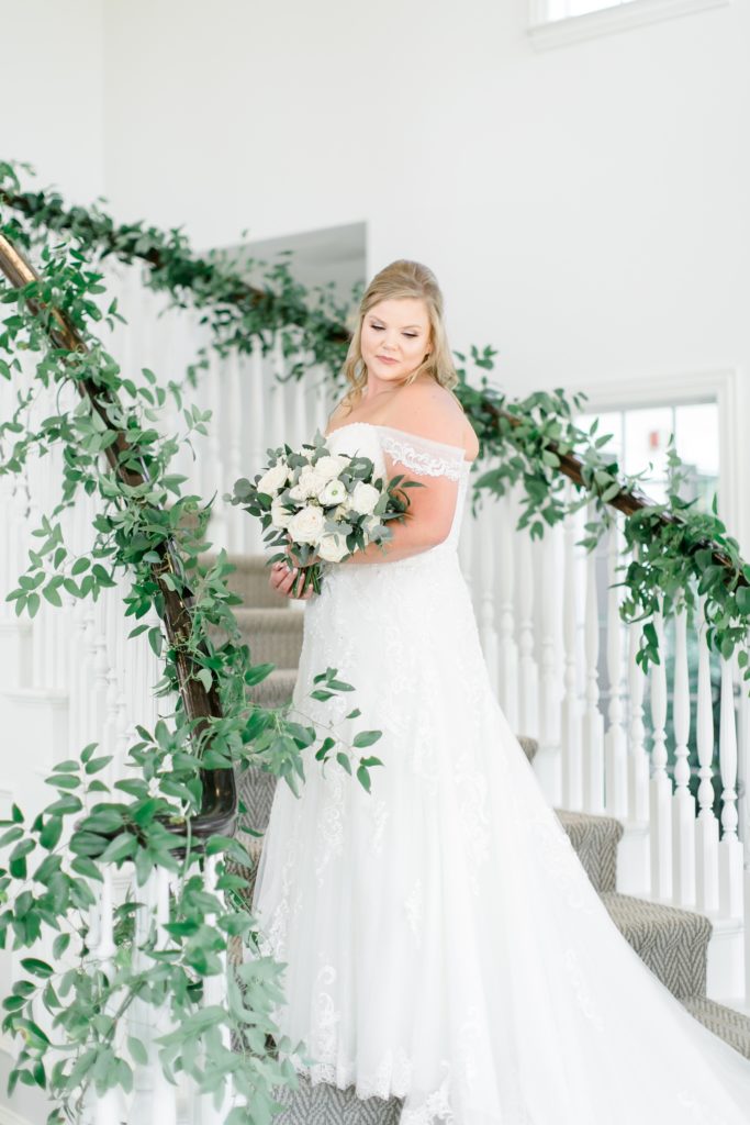 bride poses on ivy wrapped staircase