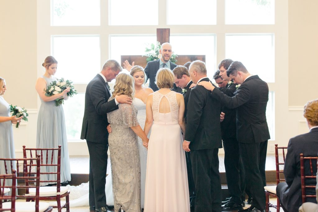 parents and families pray around bride and groom