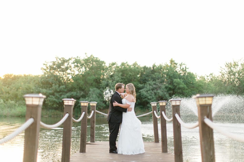 newlyweds kiss at end of dock by fountain at The Milestone Denton