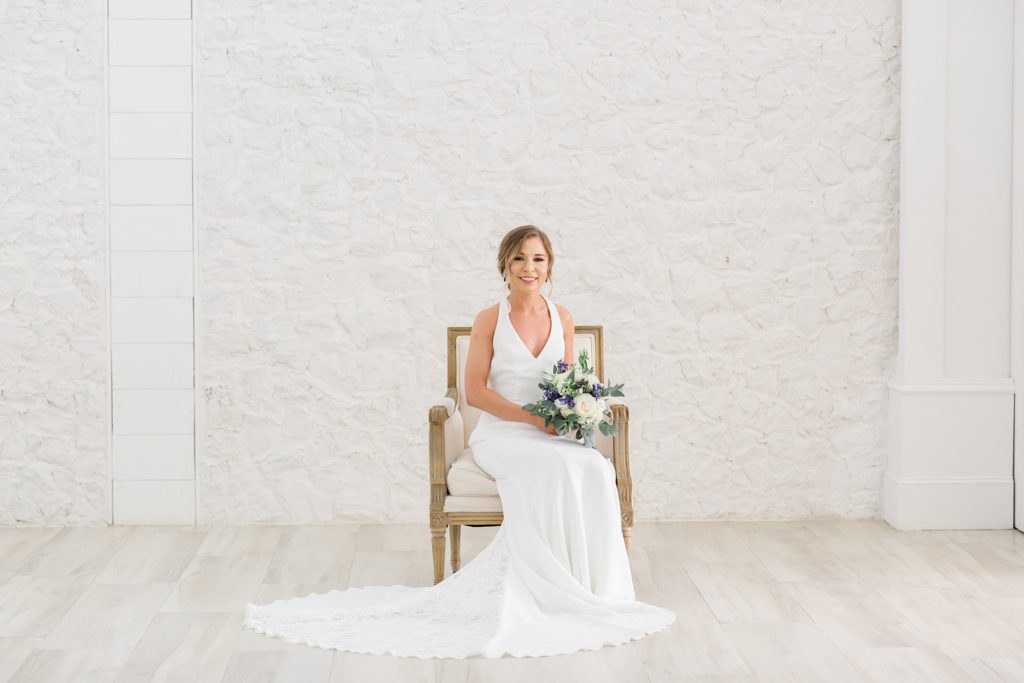 bride sits on chair with bouquet in lap