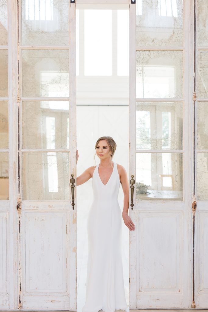 bride stands between glass doors at The Nest at Ruth Farms