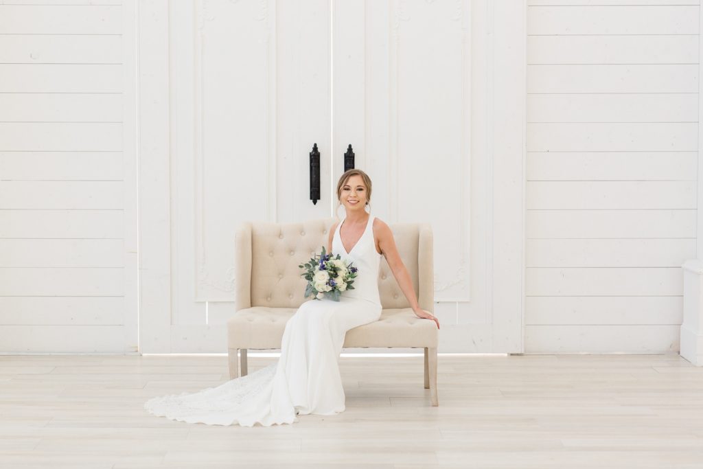 bride sits on neutral couch during bridal portraits in Texas