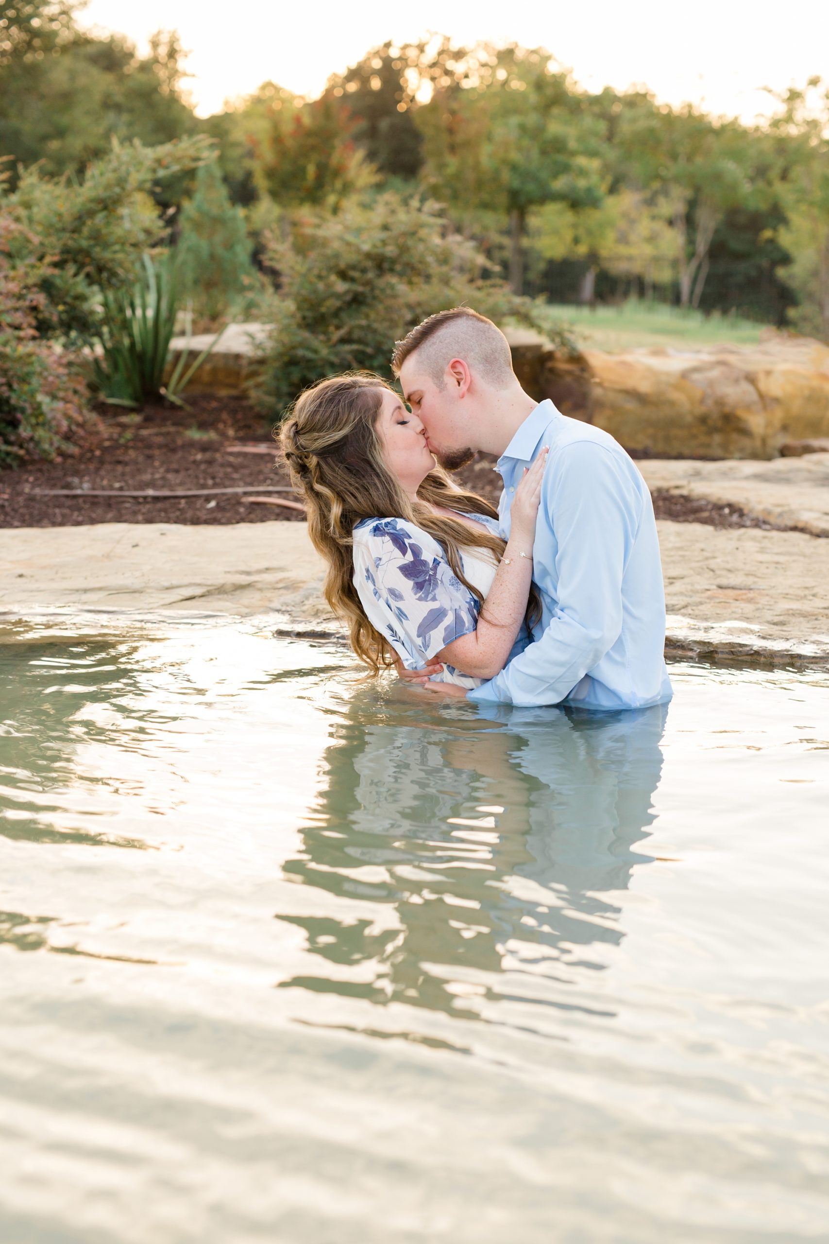 engaged couple kisses in the water at Dallas Arboretum