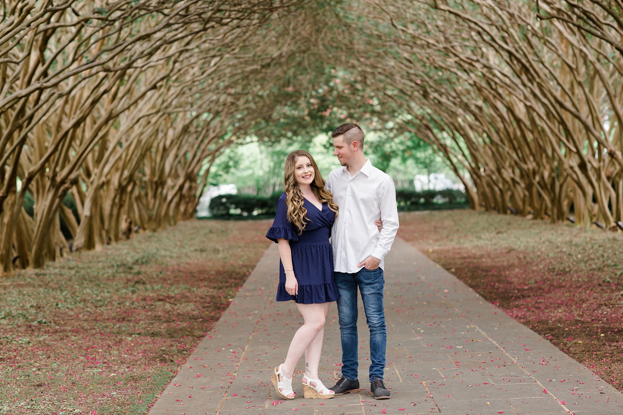 branch walkway at Dallas Arboretum with engaged couple posing underneath 