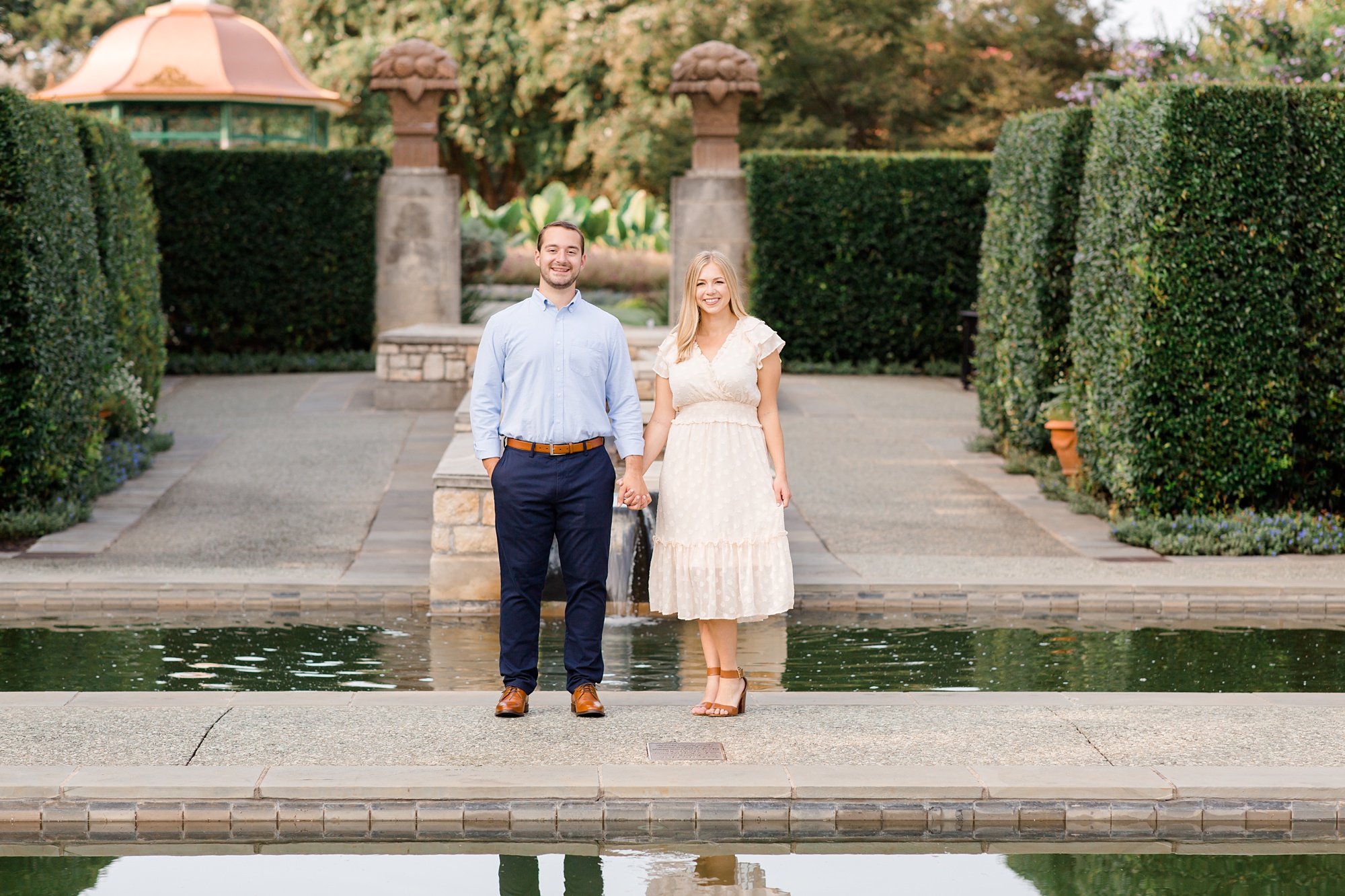bride and groom pose by reflecting pool at Dallas Arboretum