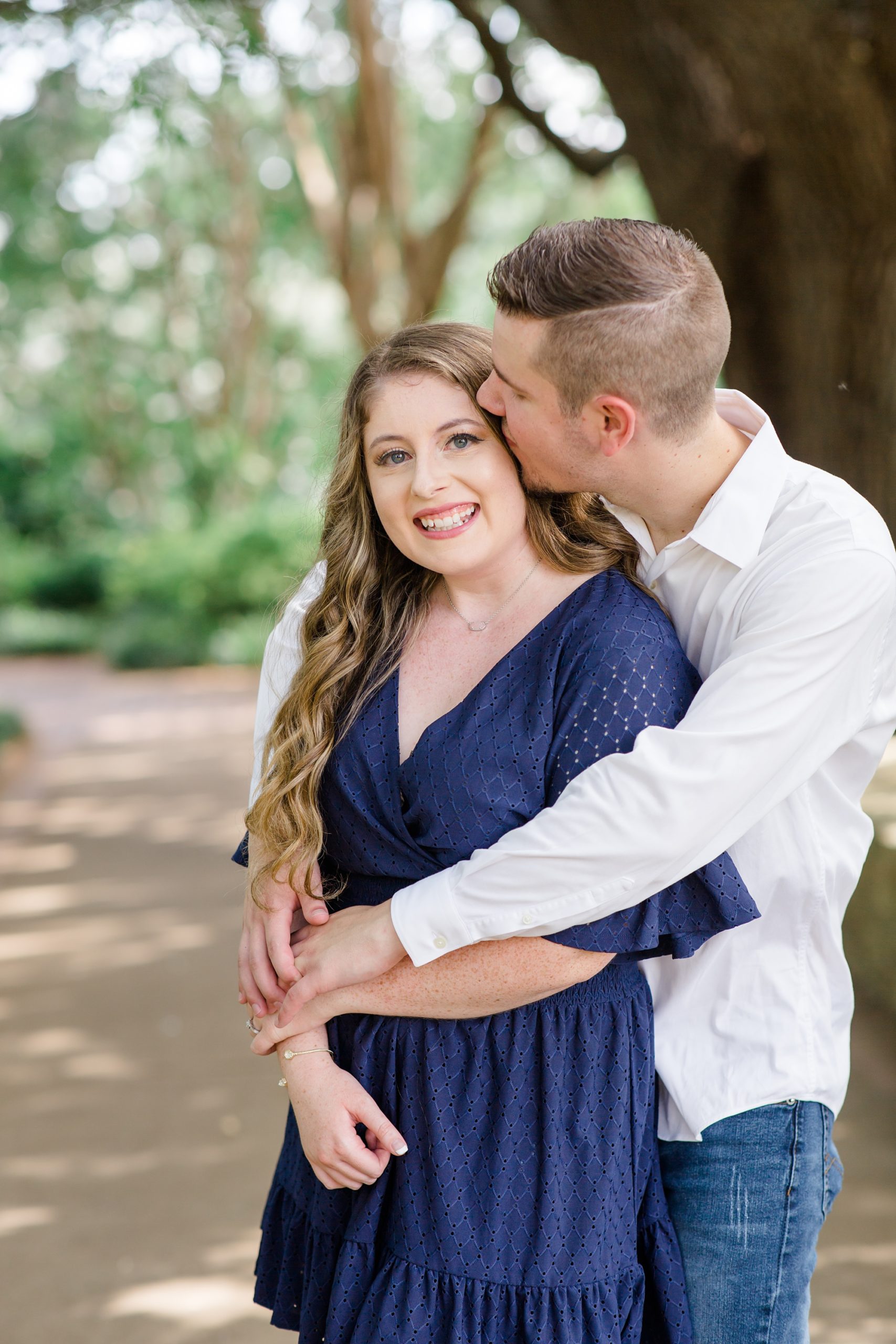 groom kisses bride's forehead during Dallas Arboretum engagement photos