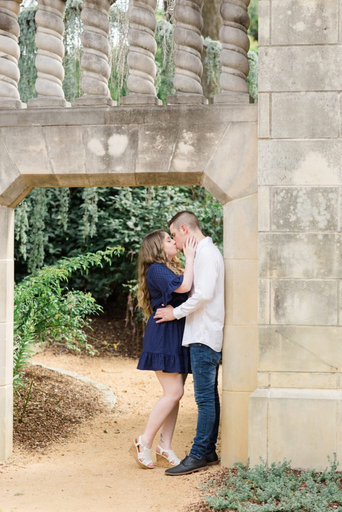 bride and groom lean against concrete archway at Dallas Arboretum