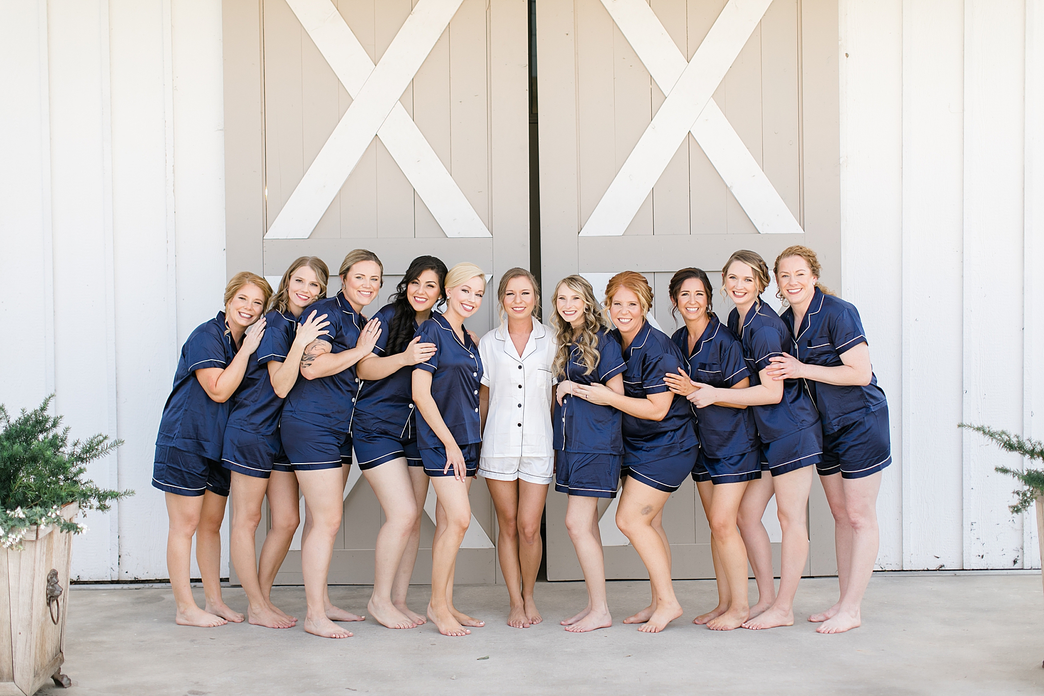 bride with bridesmaids in matching navy pajamas pose outside The Nest at Ruth Farms
