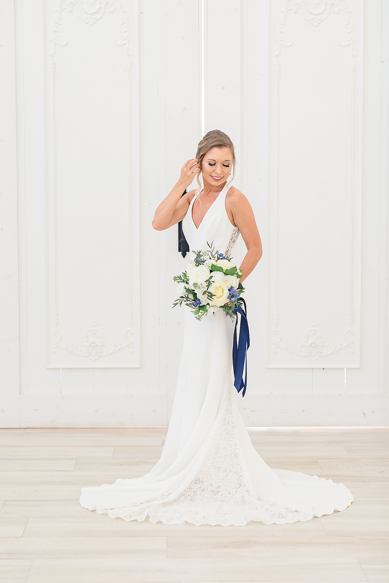 bride holds ivory bouquet with navy ribbon 
