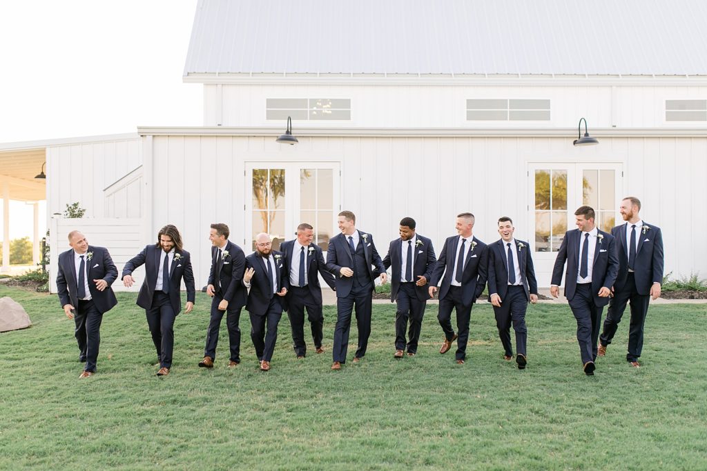 groom and groomsmen walk through field in Dallas TX