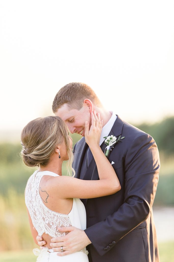 bride and groom stand nose to nose during wedding portraits