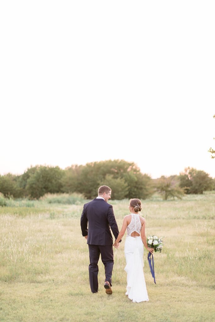 newlyweds walk through field at sunset in Dallas TX