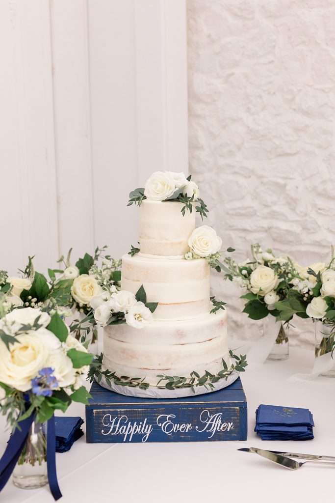 tiered wedding cake sits on distressed navy blue wooden box