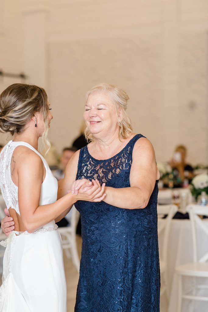 bride dances with mom in navy gown during TX wedding reception