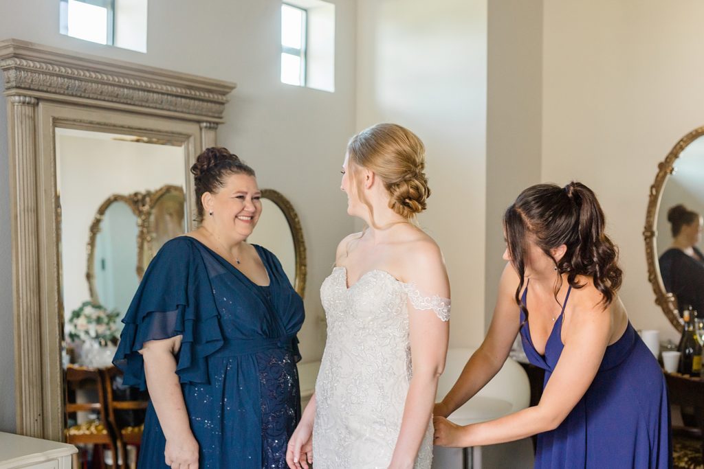 bride gets dress on with mom and bridesmaid 