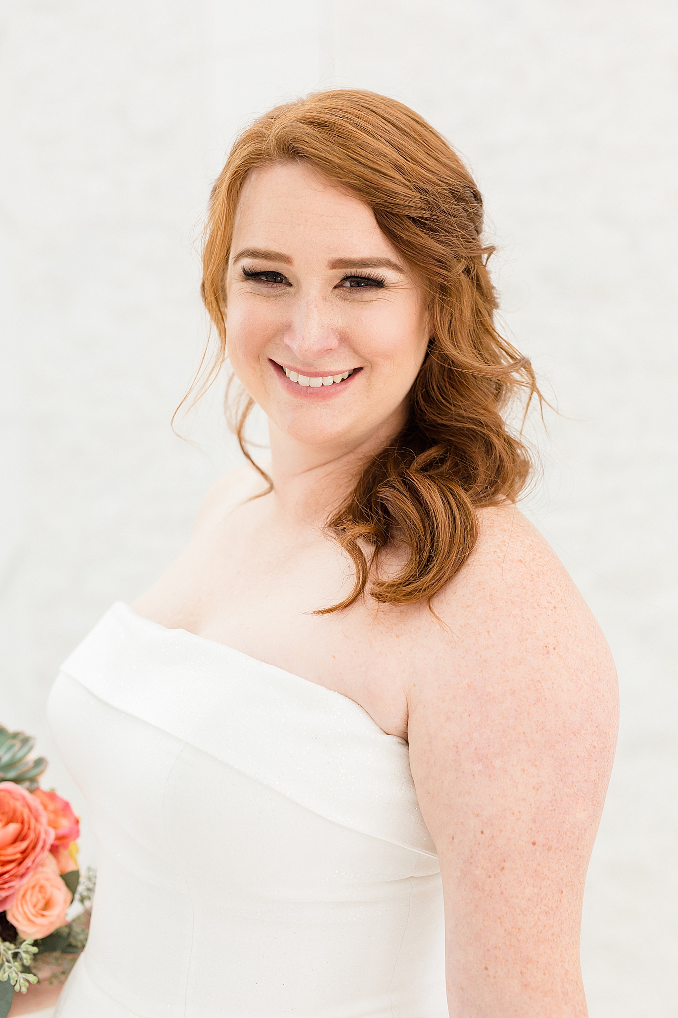 bride in strapless gown with side ponytail smiles