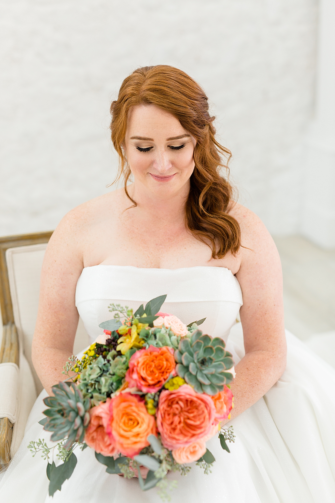 bride sits in front of doors at The Nest at Ruth Farms and looks at bouquet