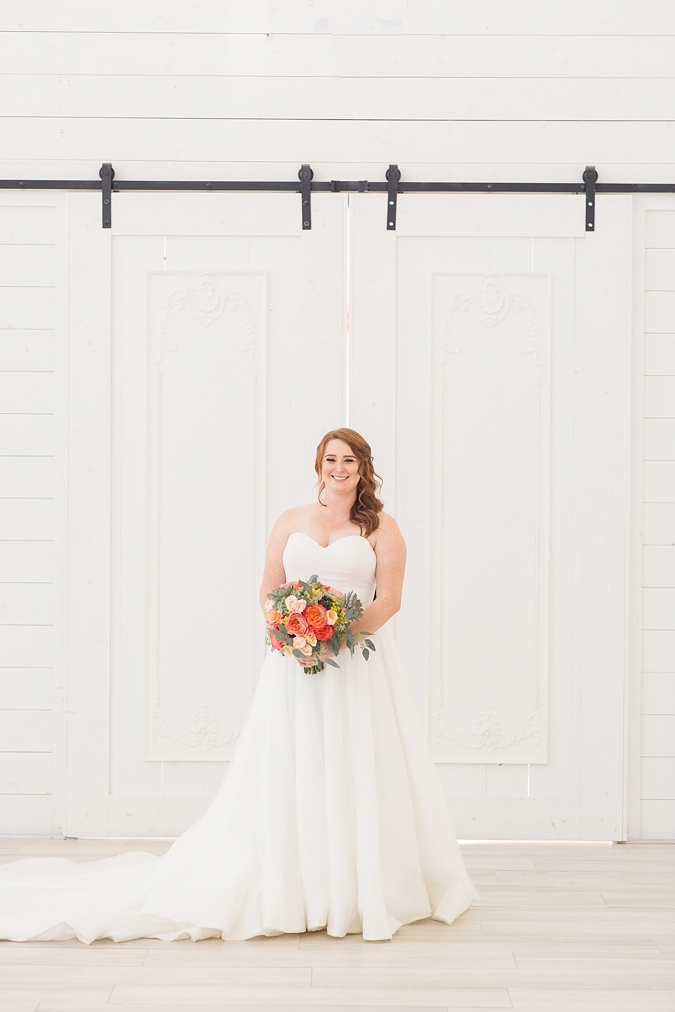 bride holds bouquet in front of barn doors at The Nest at Ruth Farms