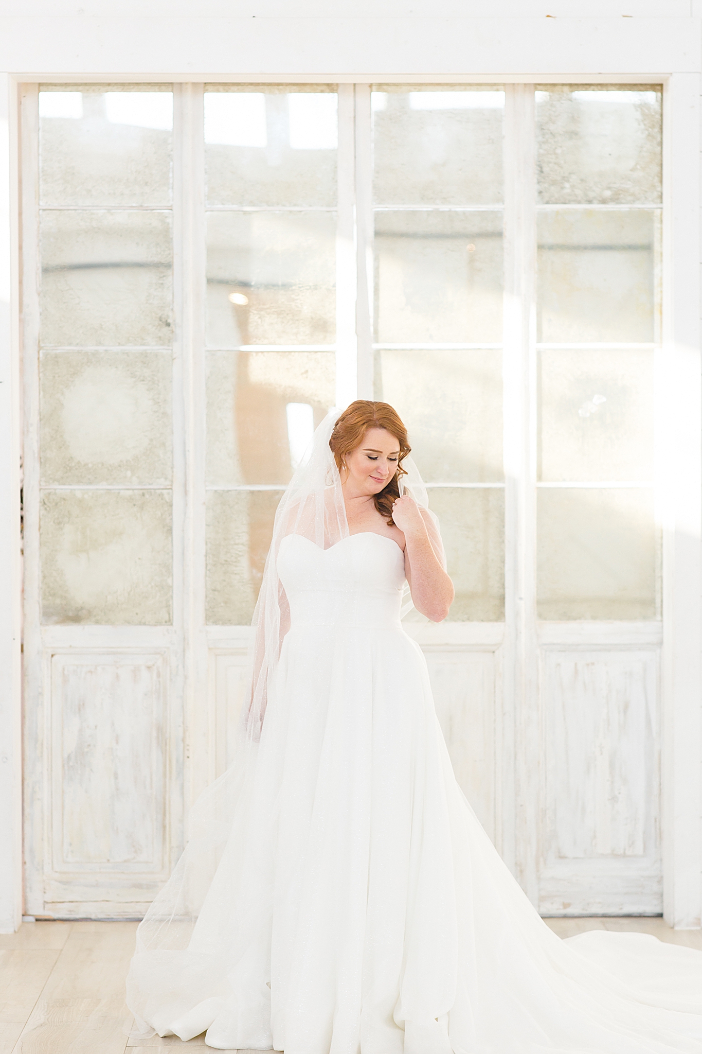 bride with veil poses in front of vintage doors