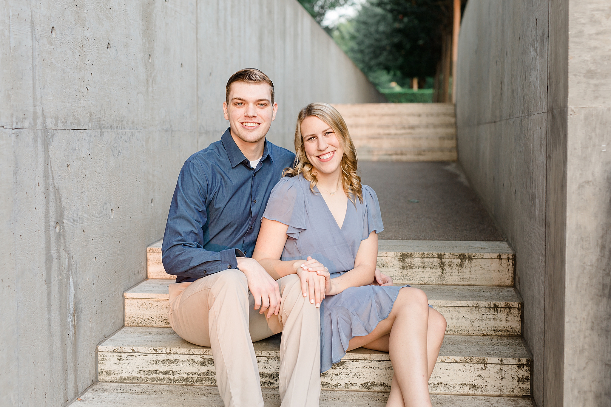 engaged couple sits on steps at Kimball Art Museum