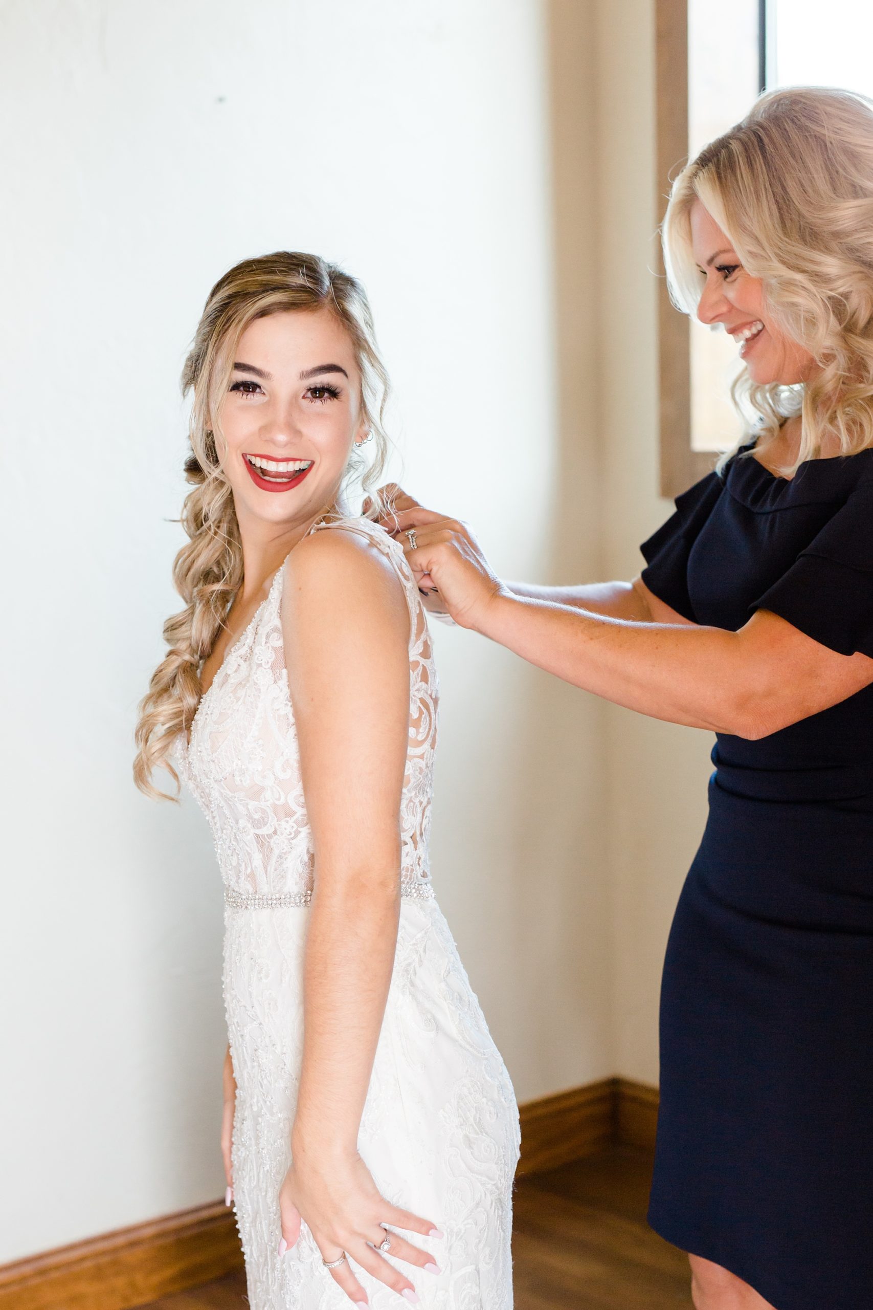 bride gets into wedding dress with mom's help