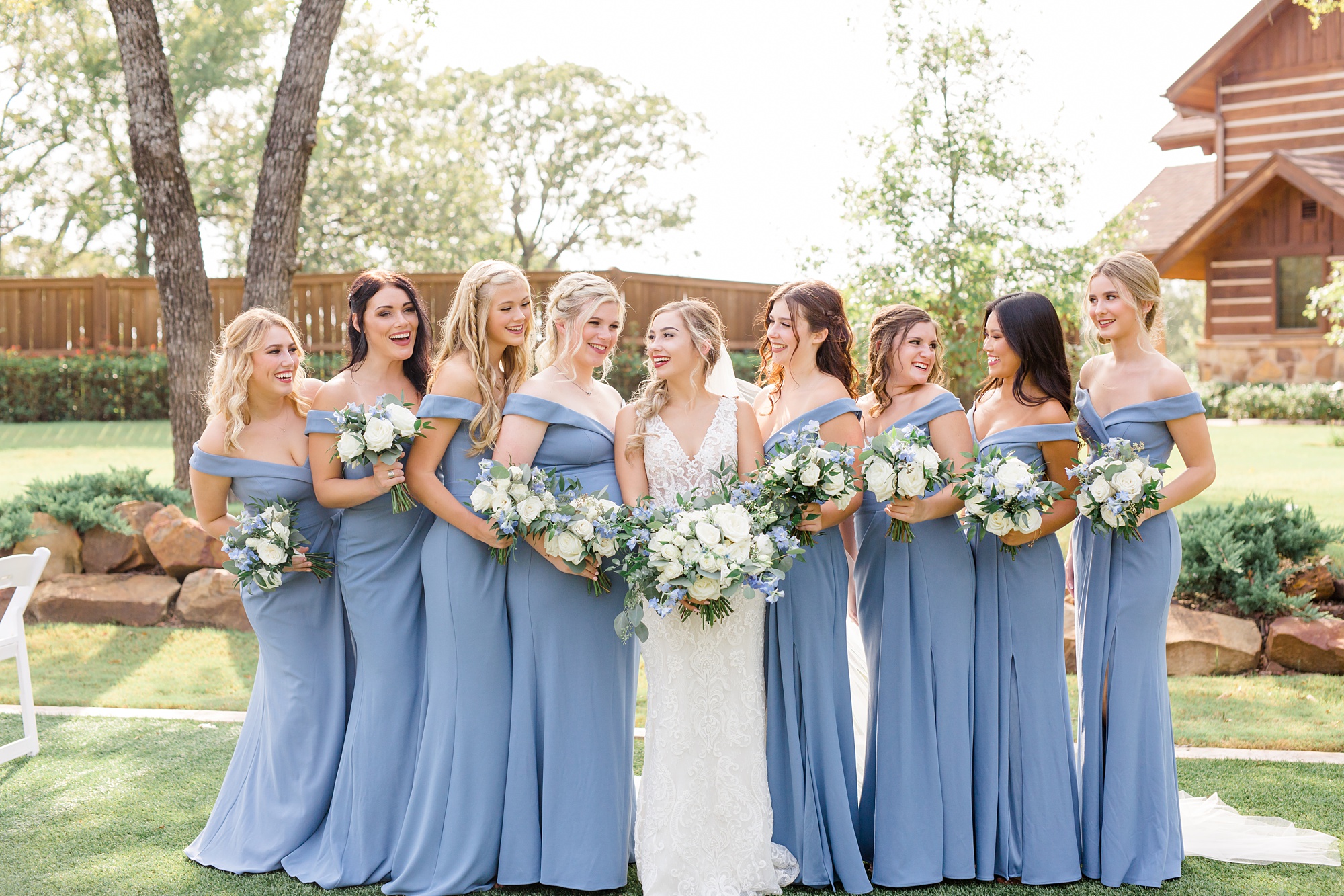 bridesmaids in blue gowns hold bouquets with white flowers