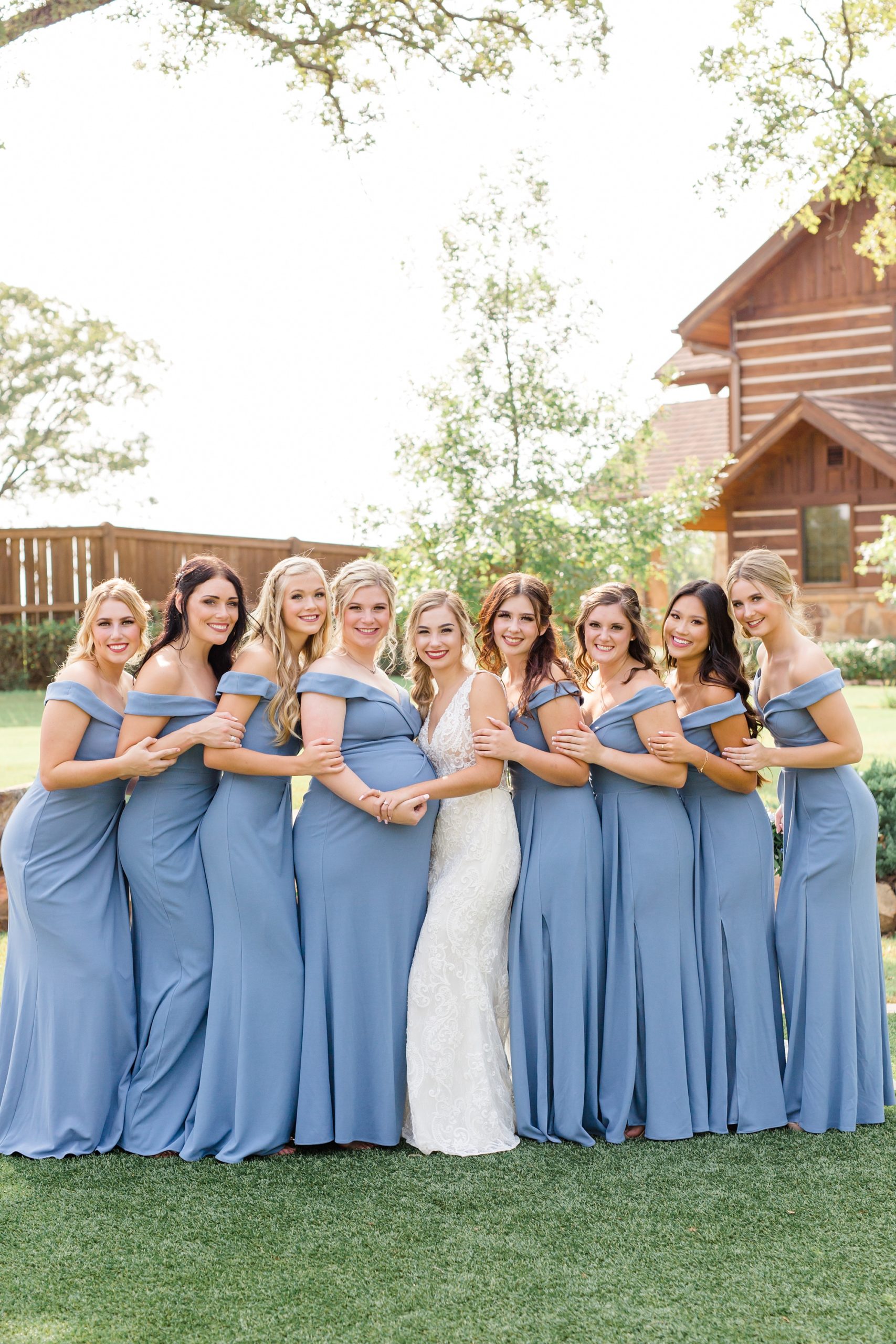 bridesmaids in light blue dresses hug bride