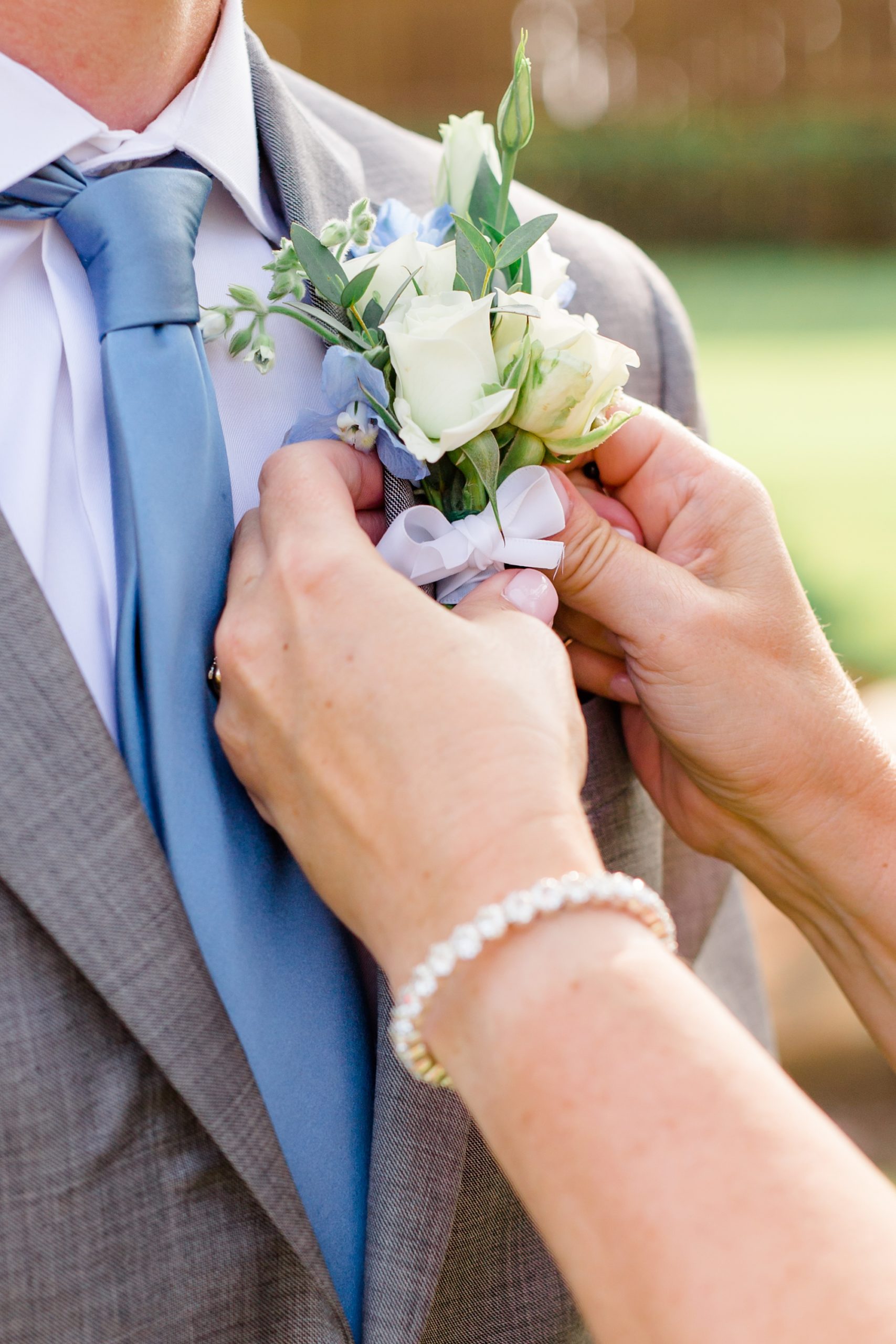 mother of groom puts on boutonnière