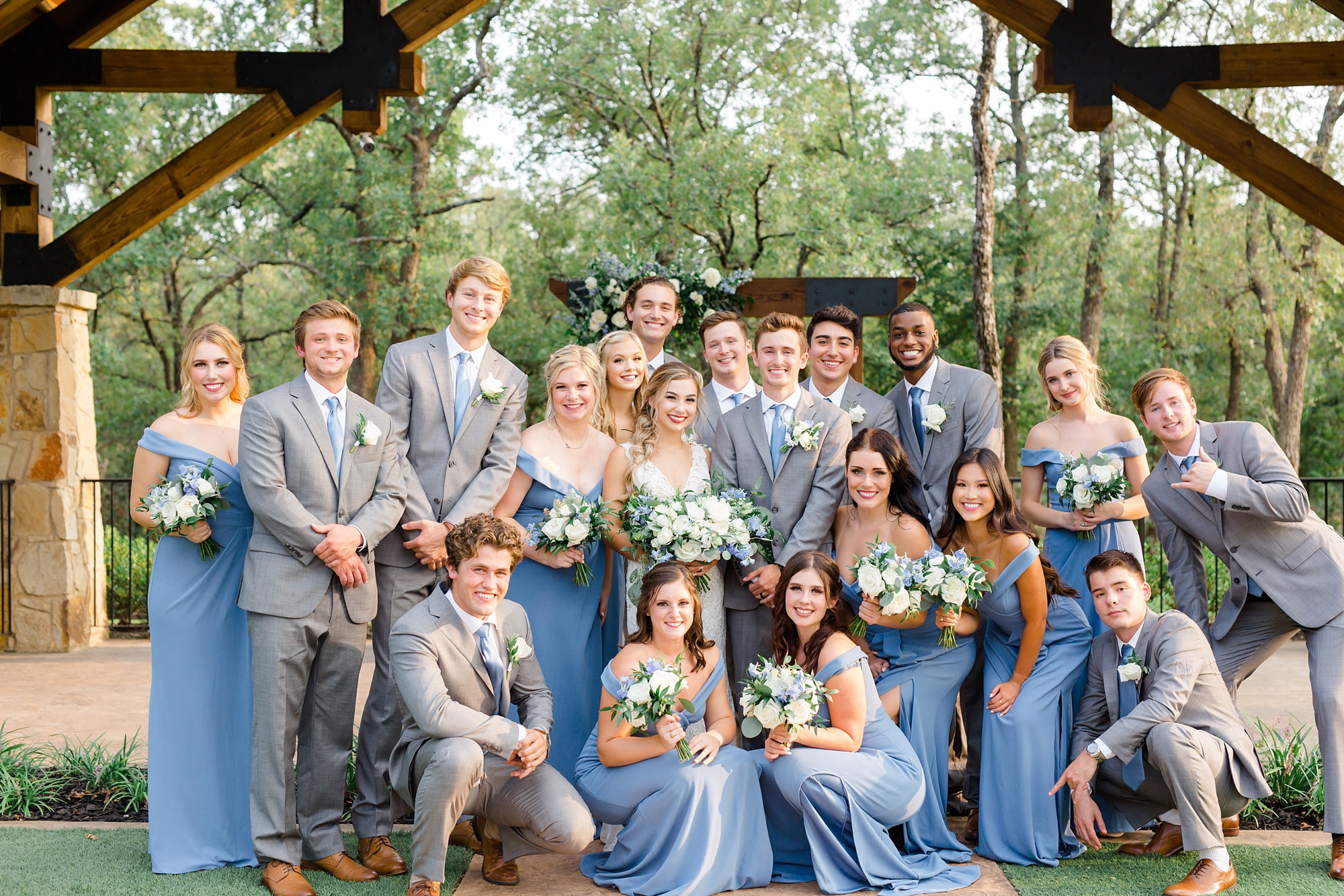 bridal party in grey and light blue poses with newlyweds